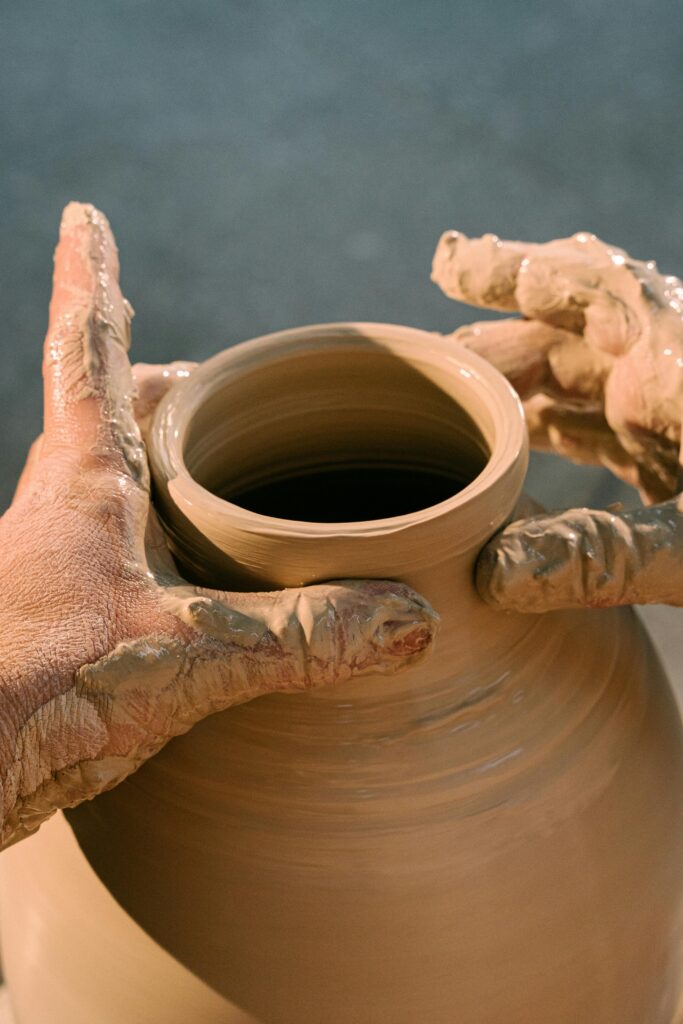 Close-up of hands molding a clay pot, highlighting the art of pottery making.